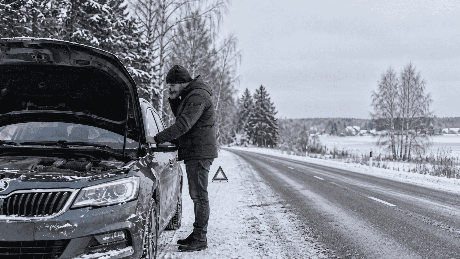 Vairuotojas telefonu kreipiasi pagalbos prie sustojusio automobilio apsnigtame kelyje